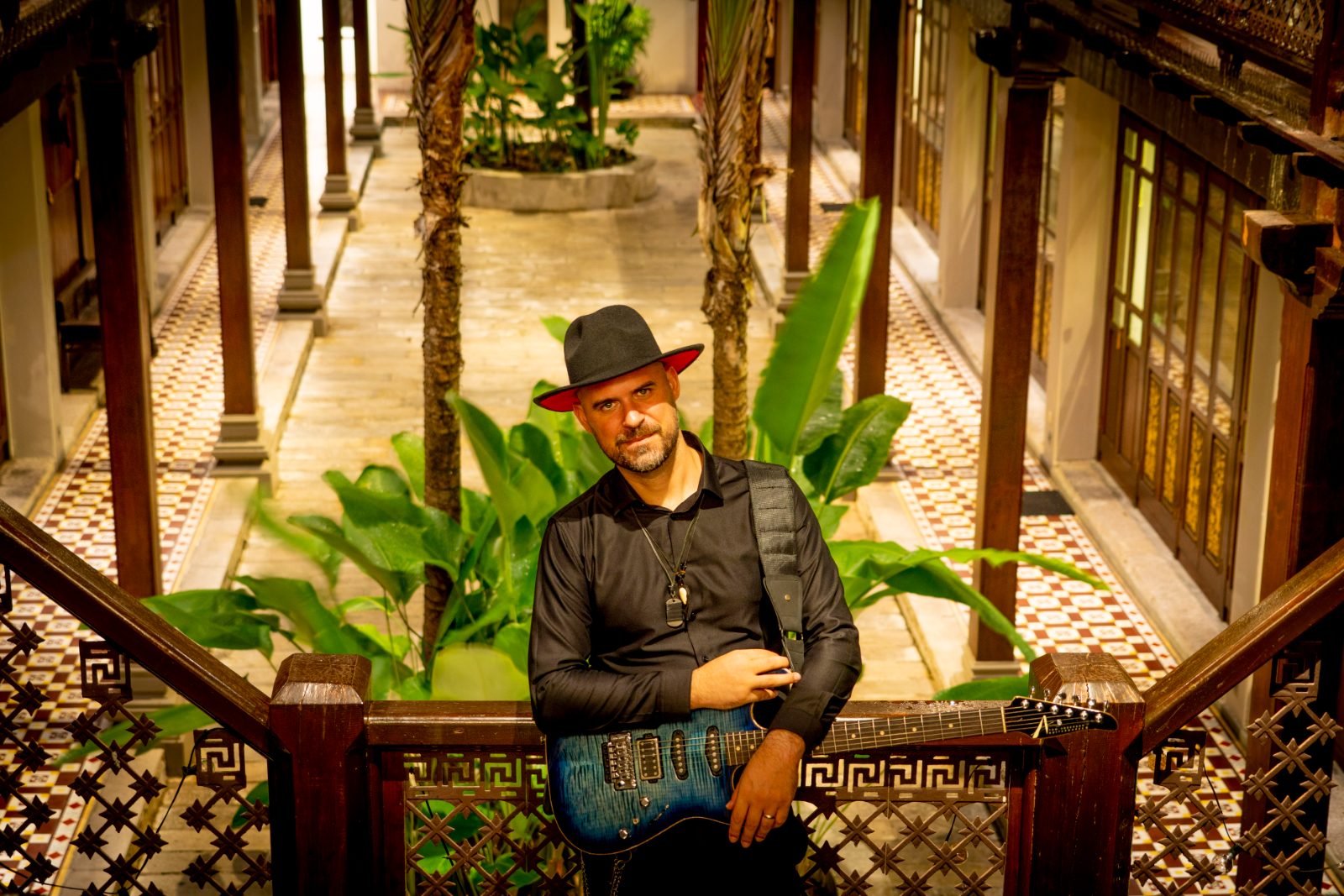 Luis Coelho playing guitar in a courtyard at golden hour